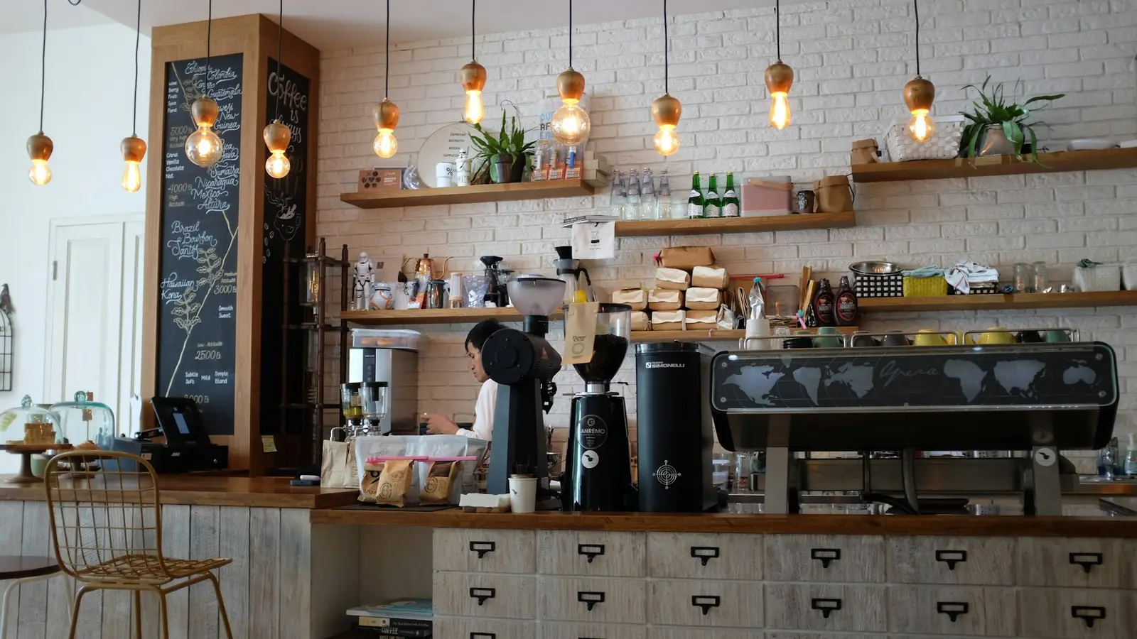 A café bar with pendant lights, shelves and an espresso machine