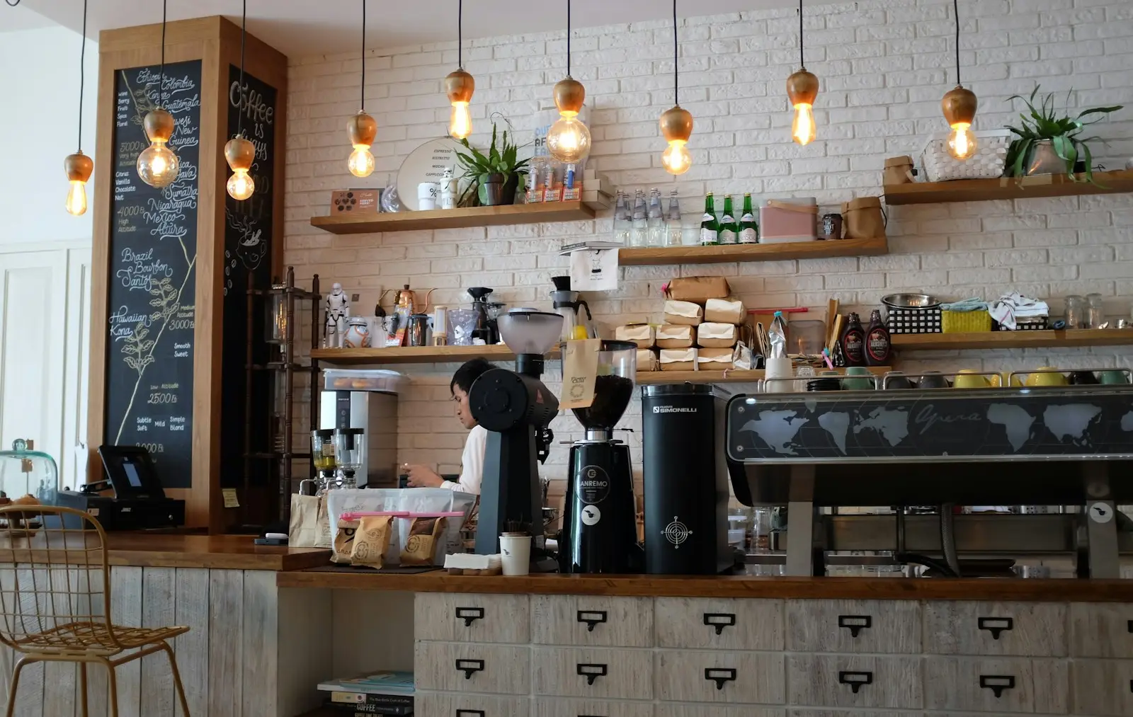 A café bar with pendant lights, shelves and an espresso machine