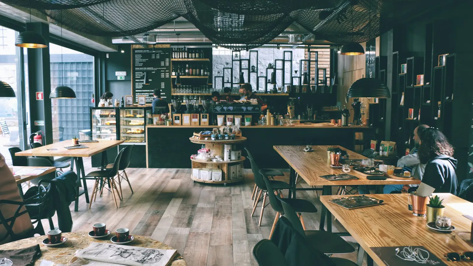 A café interior with wooden tables and large windows