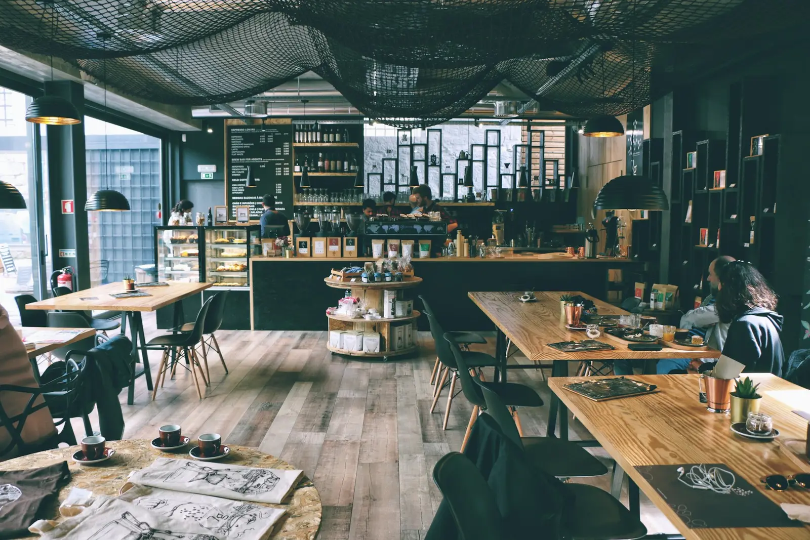 A café interior with wooden tables and large windows