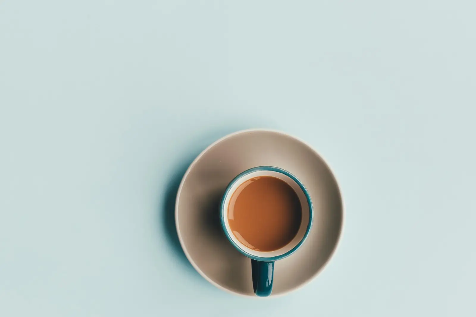 A cup of coffee seen from above on a pale blue background