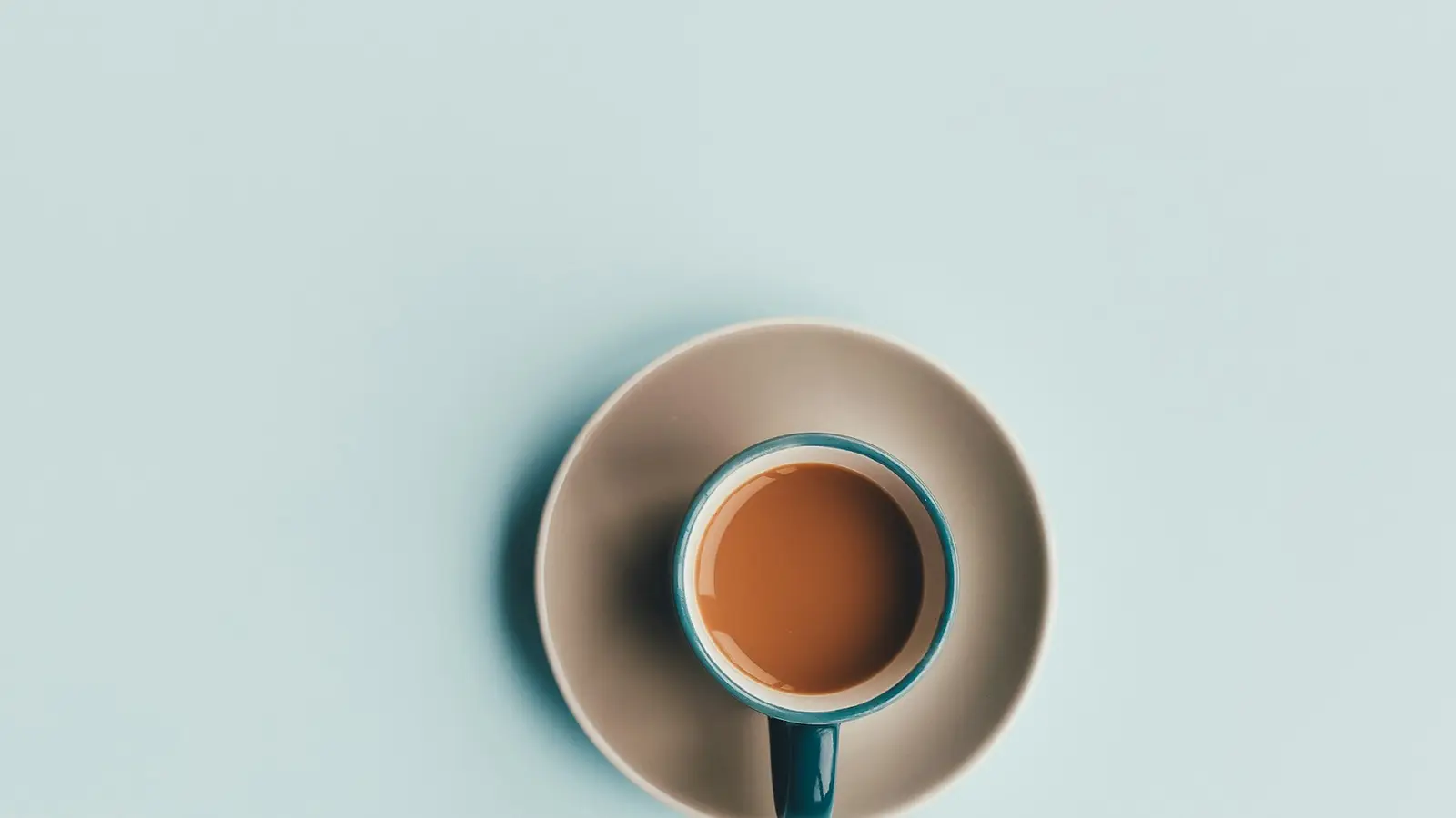 A cup of coffee seen from above on a pale blue background