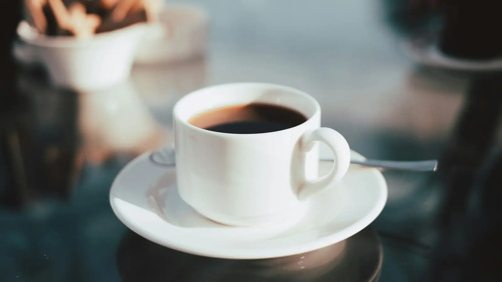 A white cup of black coffee on a saucer