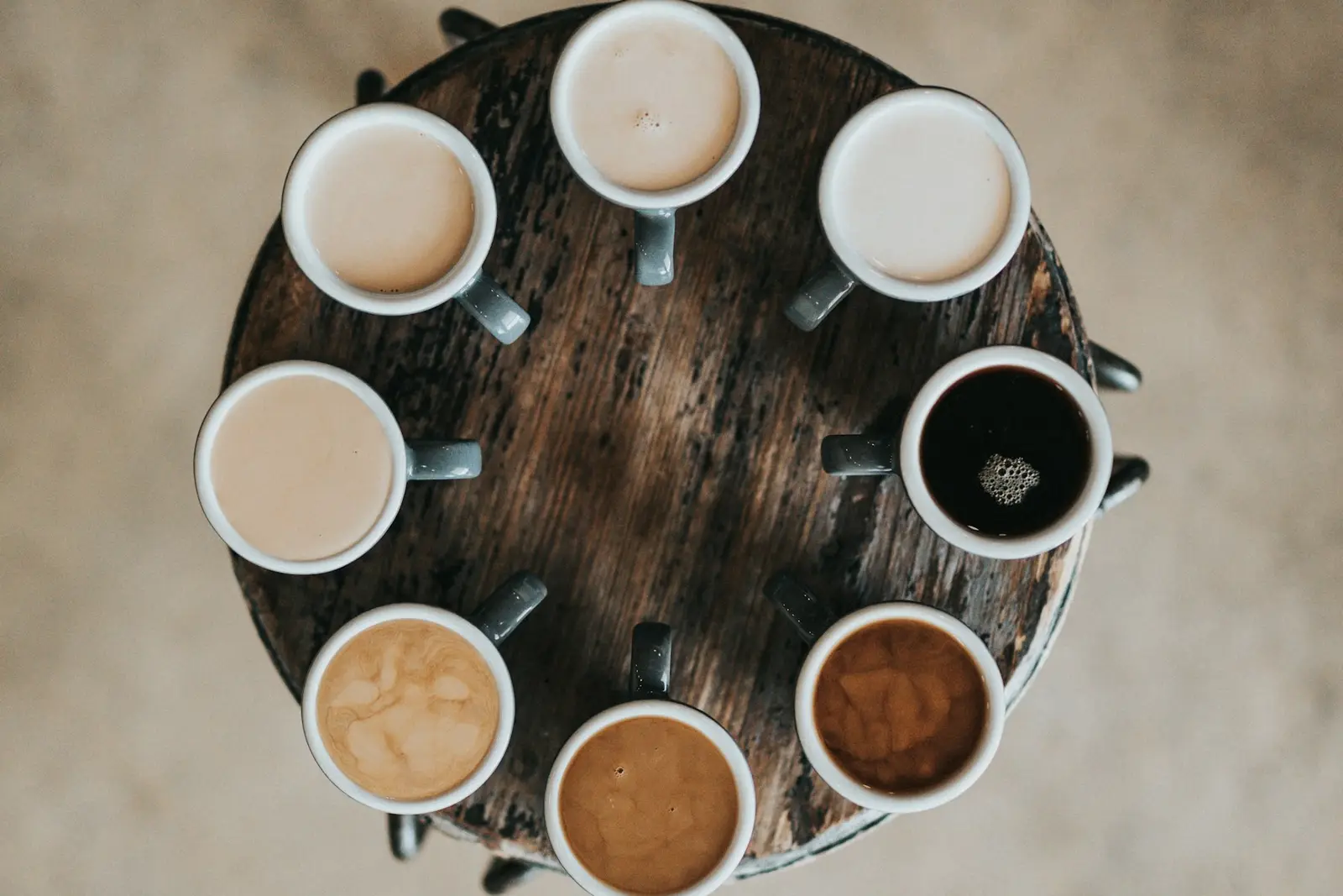 Many coffee cups arranged in a circle on a wooden table