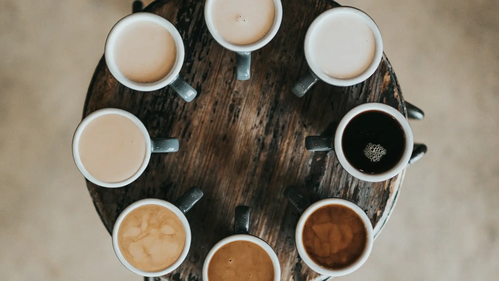 Many coffee cups arranged in a circle on a wooden table