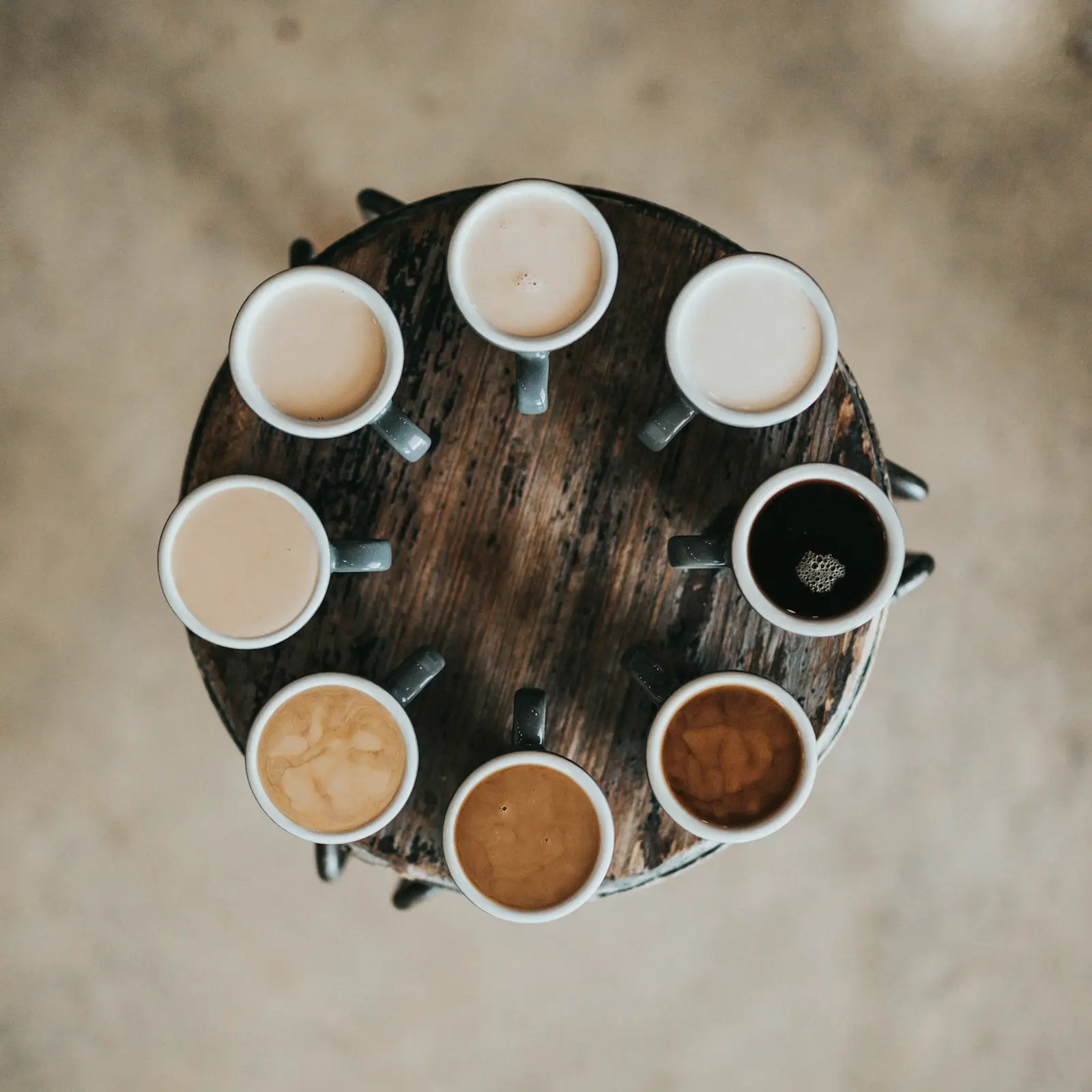 Many coffee cups arranged in a circle on a wooden table