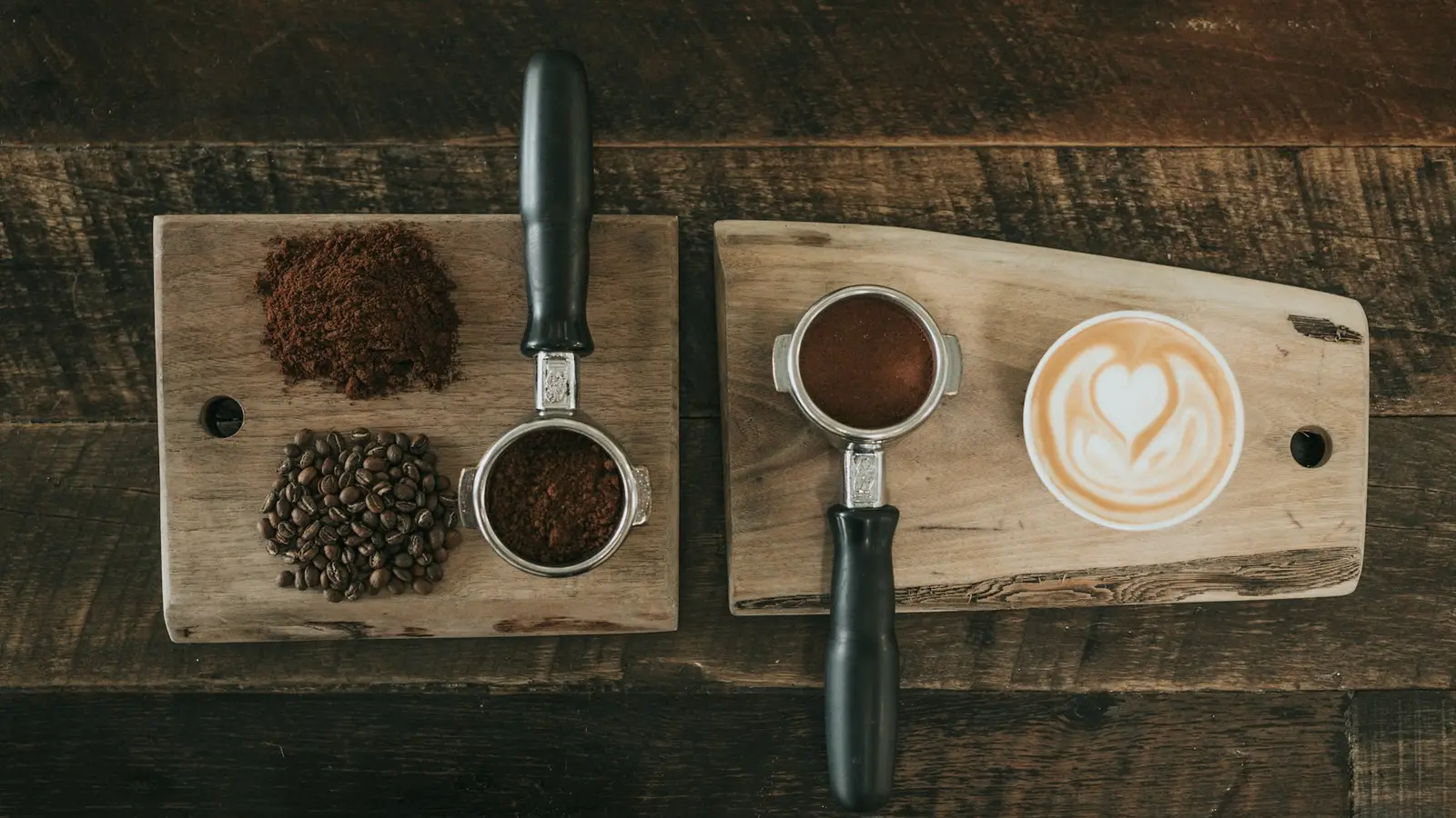 Ground coffee and whole beans on a wooden board beside a portafilter
