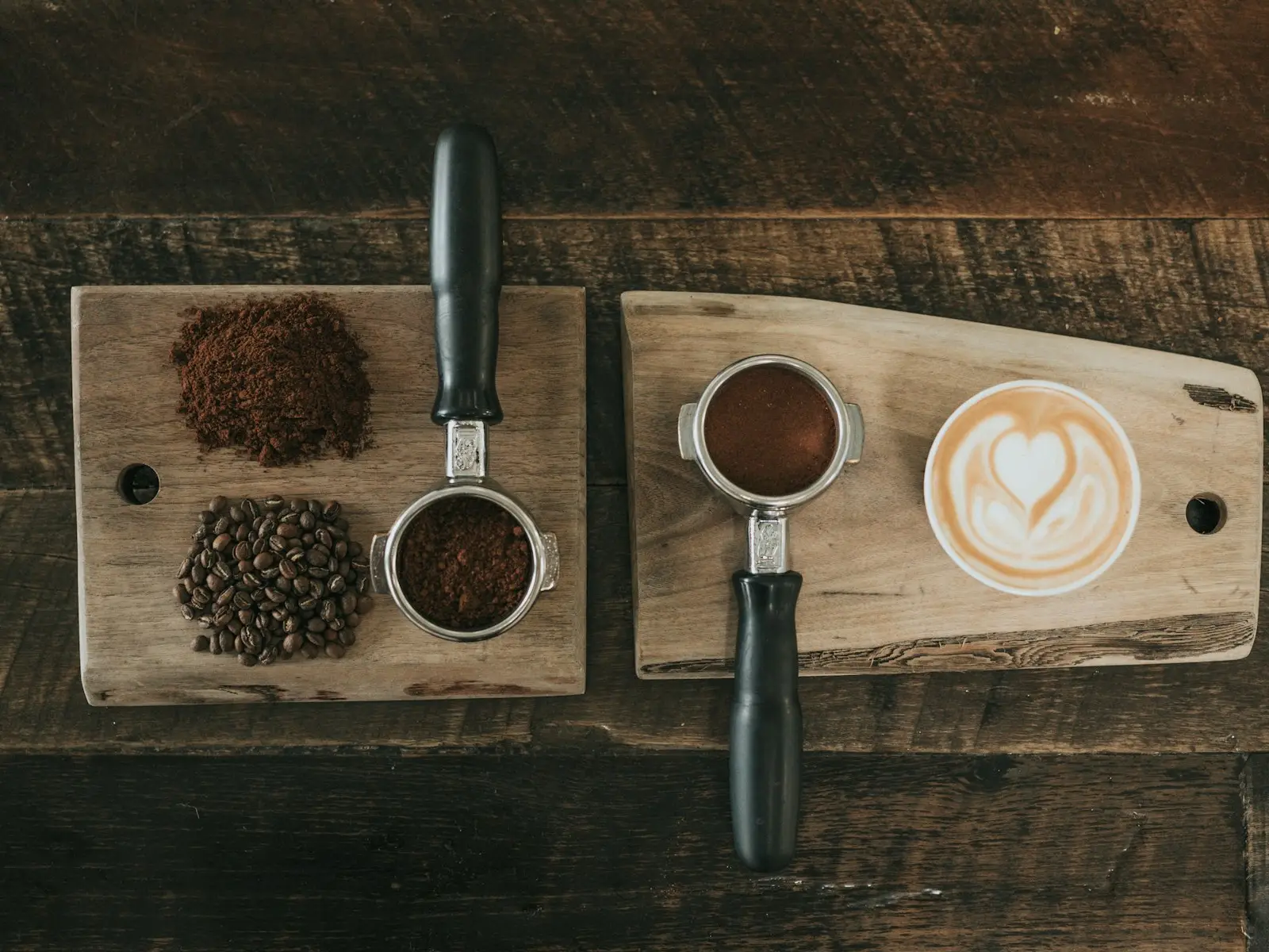 Ground coffee and whole beans on a wooden board beside a portafilter