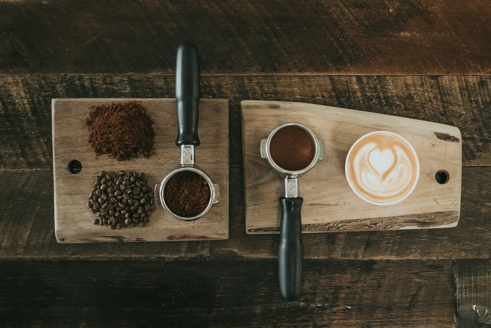 Ground coffee and whole beans on a wooden board beside a portafilter