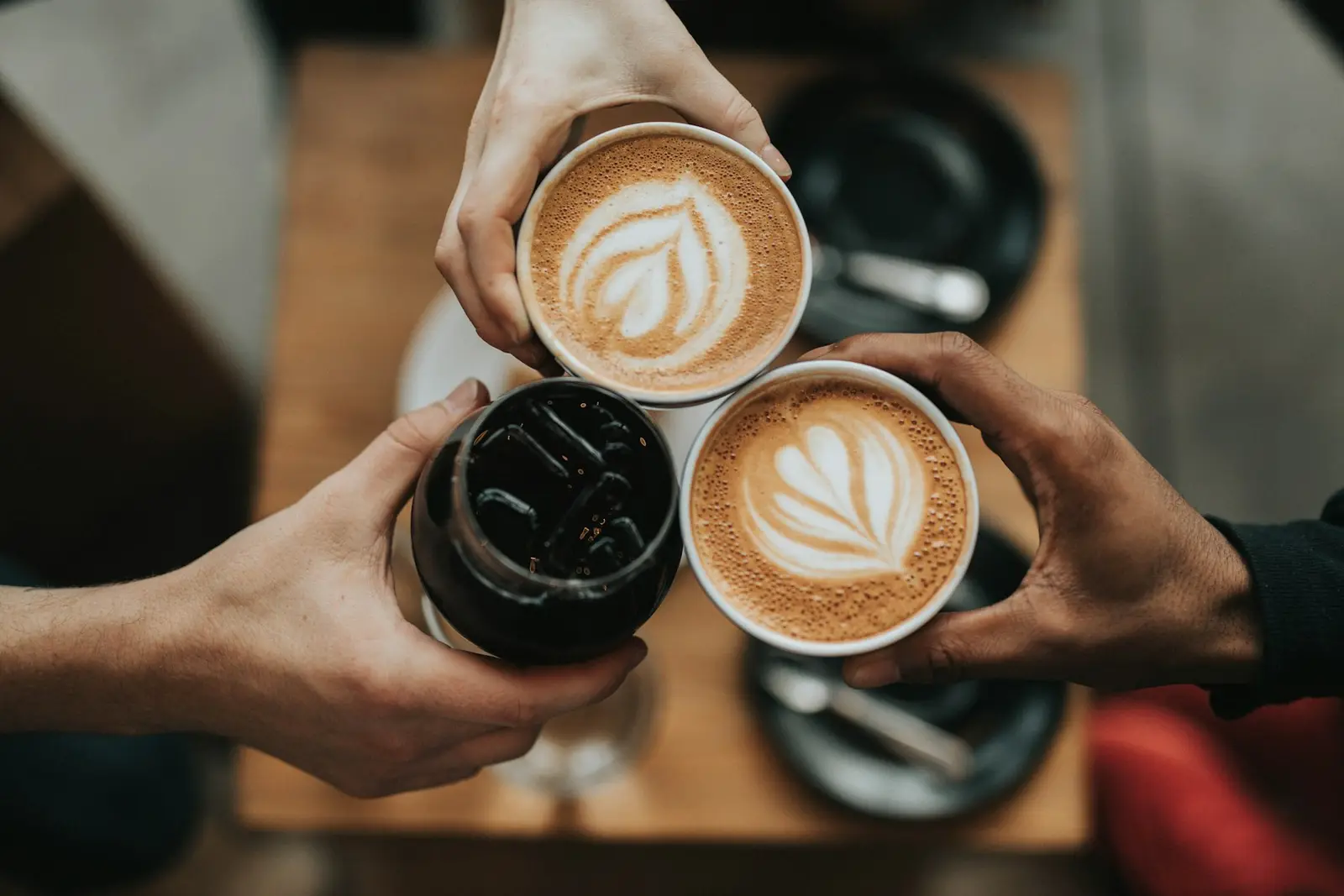Two people toasting with latte art cups