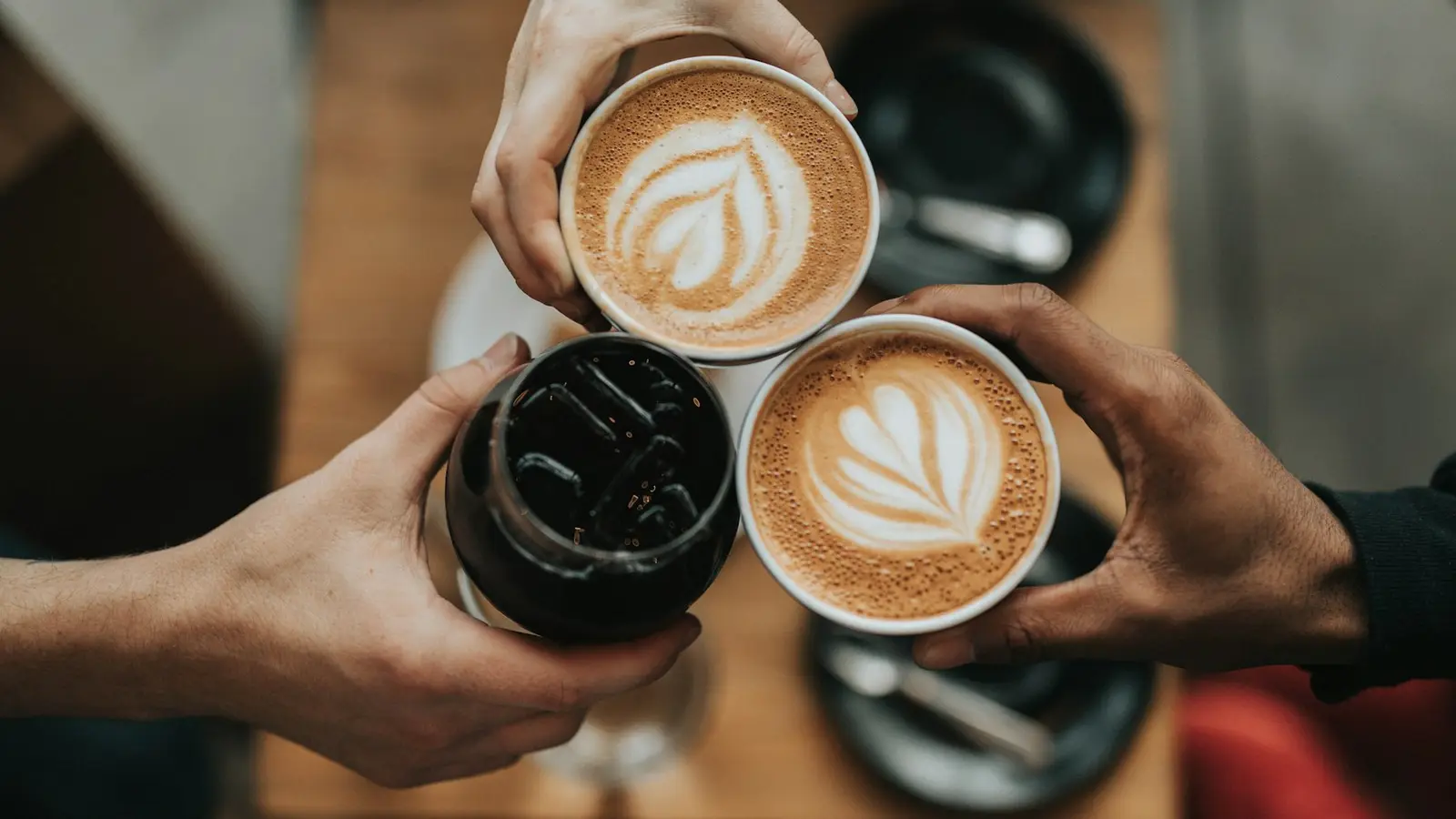 Two people toasting with latte art cups