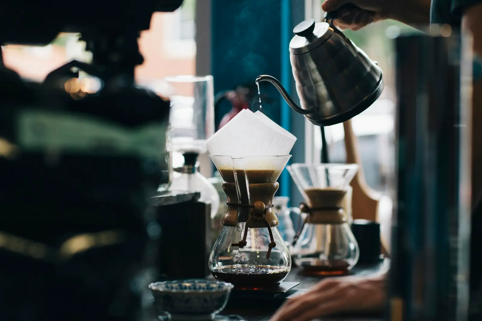 A glass pour-over brewer and kettle on a counter