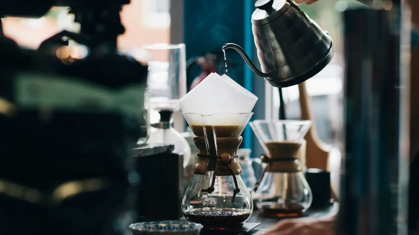 A glass pour-over brewer and kettle on a counter